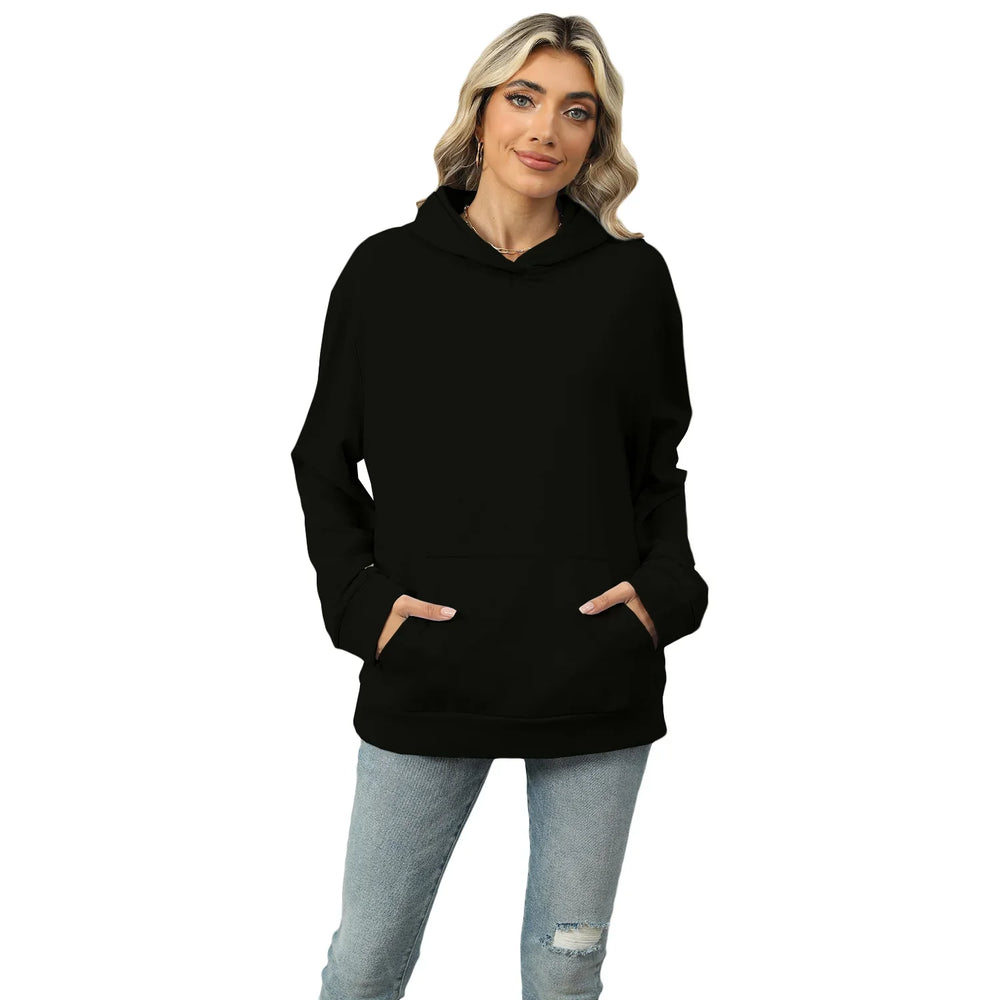 Woman wearing plain black hoodie with front pockets and light ripped jeans on white background