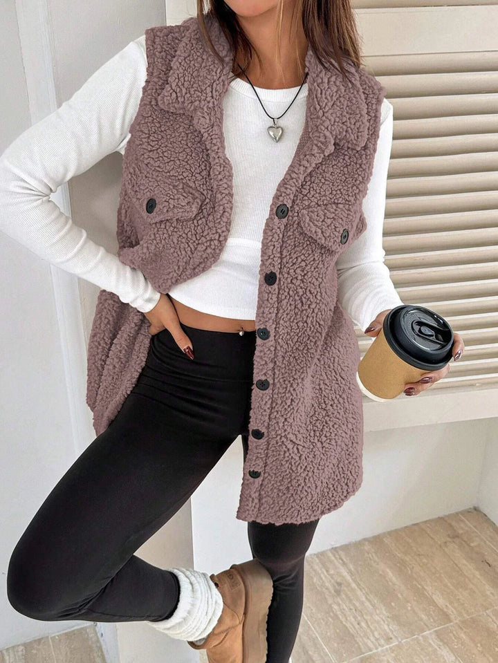 Woman wearing a mauve sherpa button vest over white crop top and black leggings, holding a coffee cup