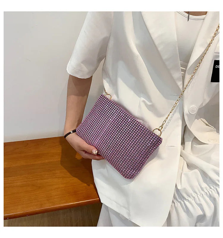 Woman in white outfit holding pink and black checkered crossbody bag with gold chain strap