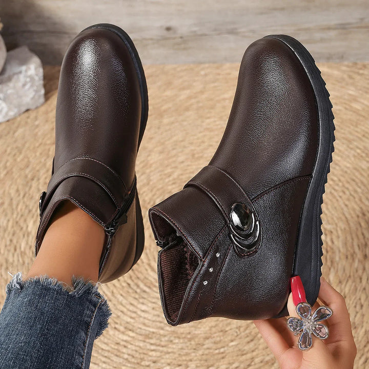 Stylish dark brown leather ankle boots with side zipper and decorative buckle on woven mat