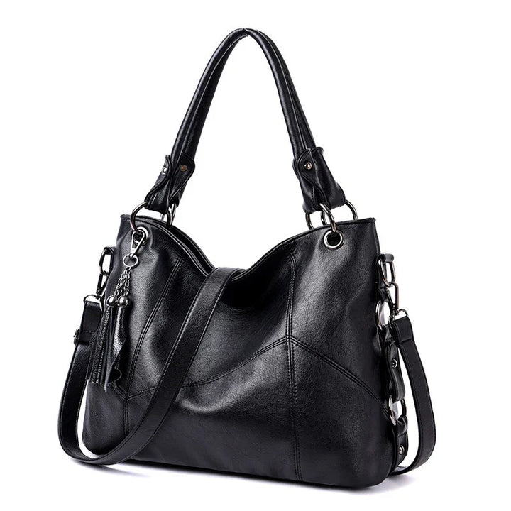 Black leather tote handbag with dual handles, detachable shoulder strap, and tassel detail
