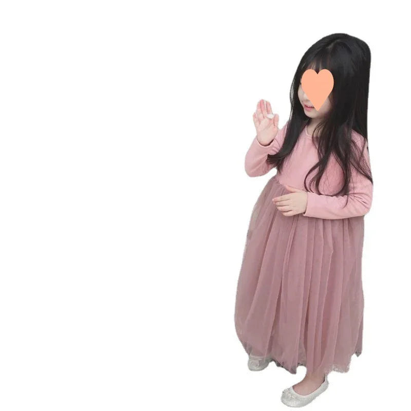 Young girl wearing long pink tulle dress and silver shoes on white background