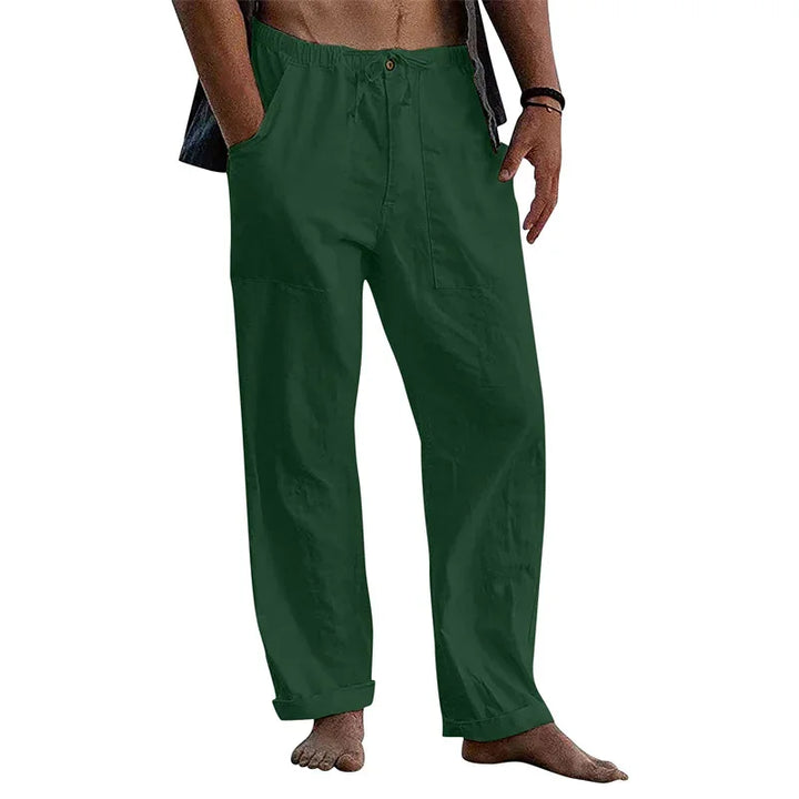 Man wearing green casual loose fit pants with elastic waist and button, standing barefoot