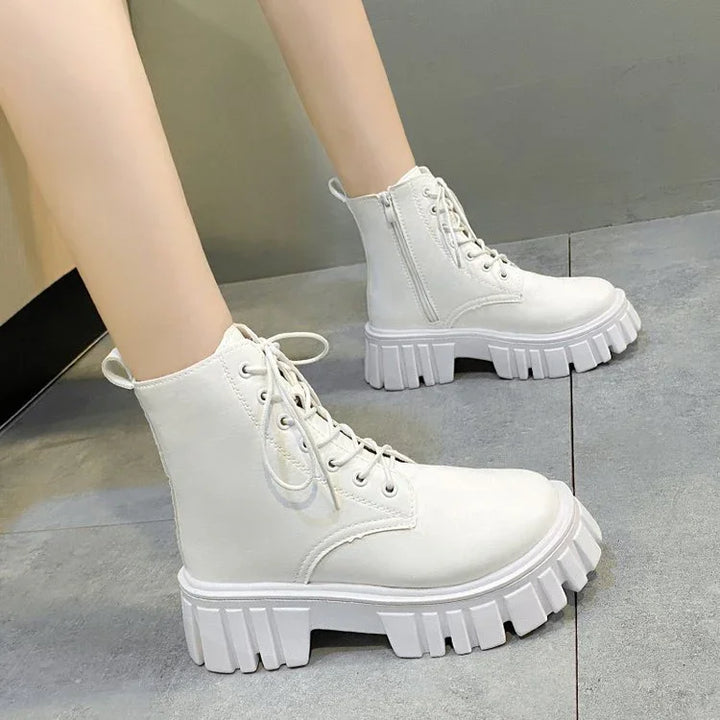White chunky platform combat boots with lace-up and side zipper on grey floor