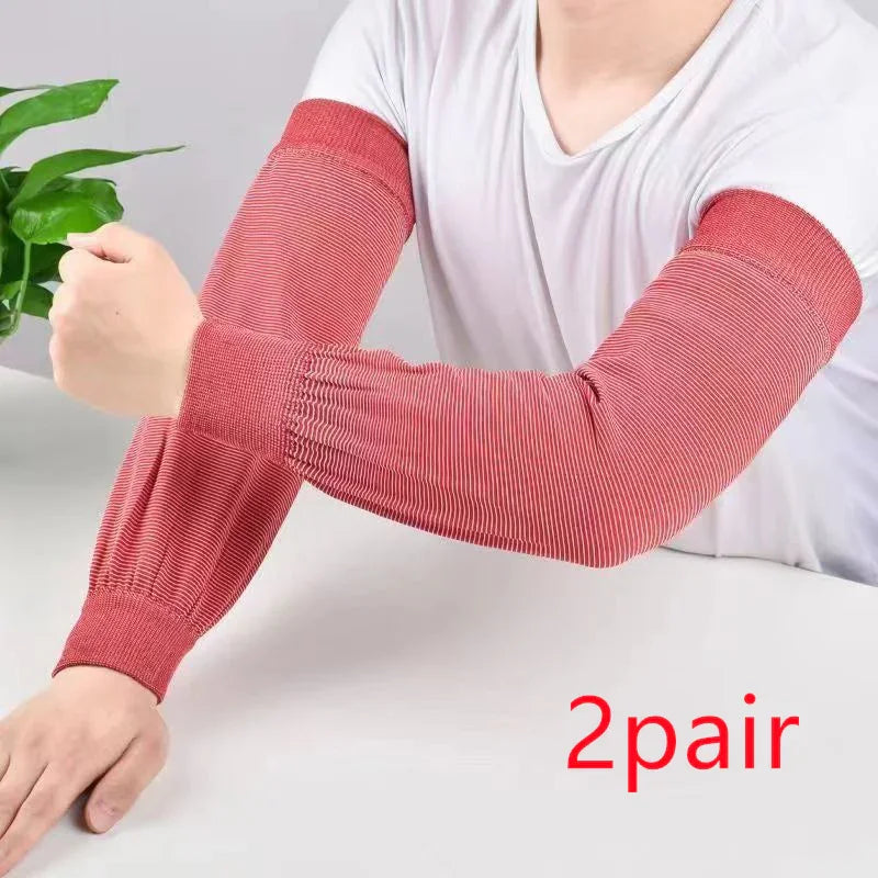 Person wearing red striped arm sleeves on both arms over white shirt next to green plant