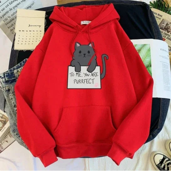 Red hoodie with a gray cat holding a sign that says 'To me, you are purrfect' laid on denim and papers