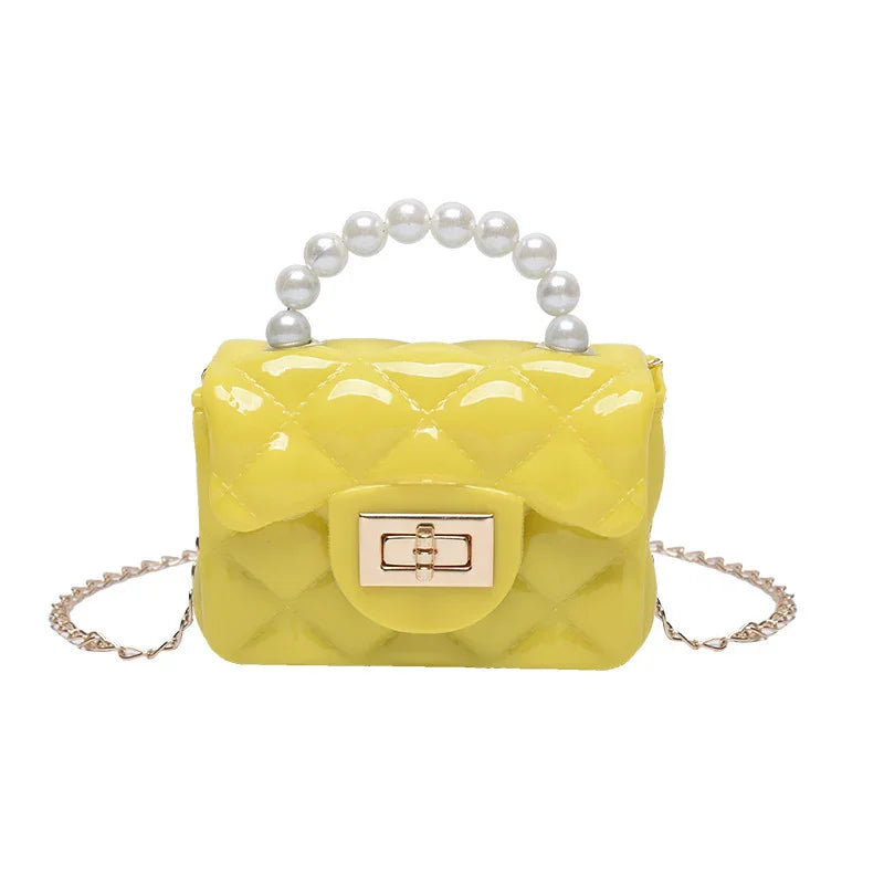 Yellow quilted handbag with pearl handle and gold chain strap on white background
