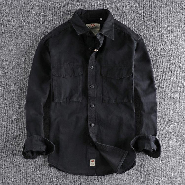 Black long-sleeve button-up shirt with chest pockets on grey fabric background