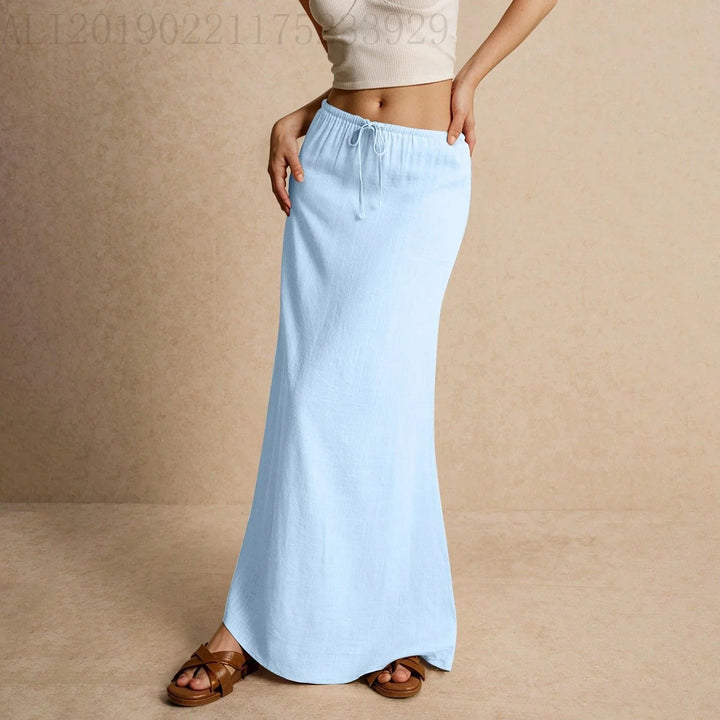Woman wearing a light blue maxi skirt with drawstring waist and brown sandals on beige background