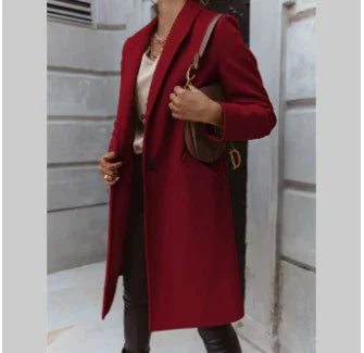 woman wearing a stylish deep red long coat with pockets and a brown shoulder bag in an urban setting