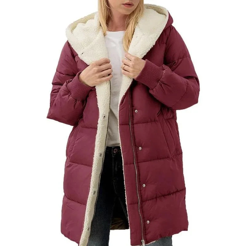 Woman wearing a long burgundy puffer coat with white sherpa lining and hood, paired with jeans
