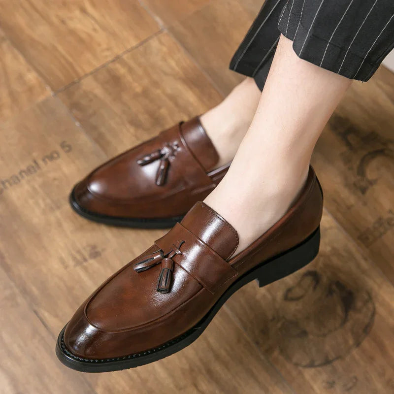Brown leather tassel loafers worn with striped trousers on wooden floor