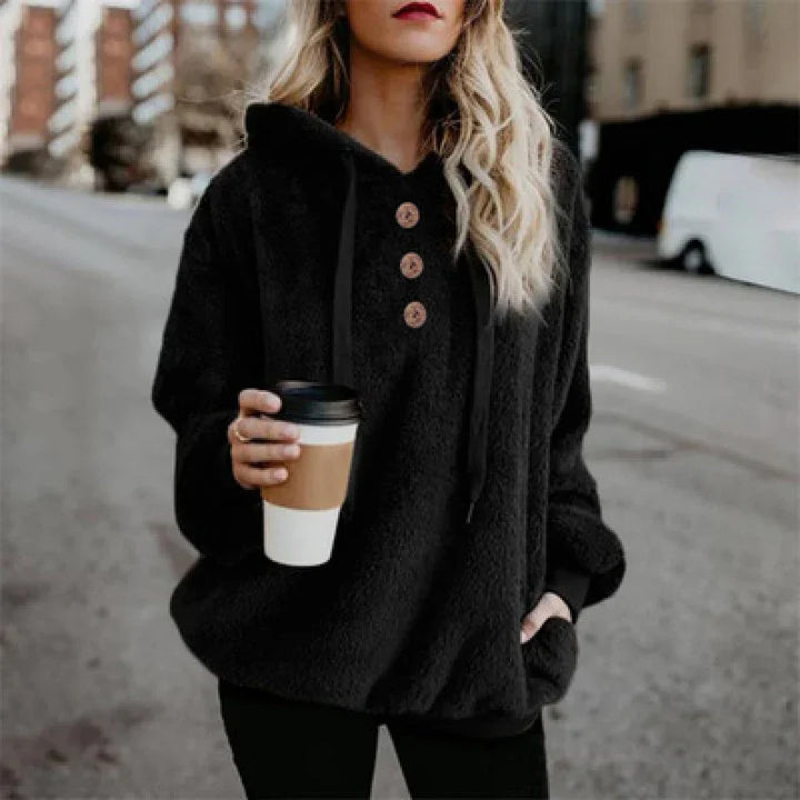 Woman wearing black buttoned hoodie holding coffee cup on urban street