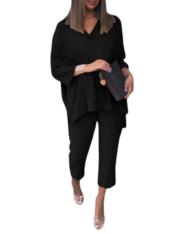 Woman in black loose fit top and cropped pants outfit with clear high heel sandals holding a black clutch