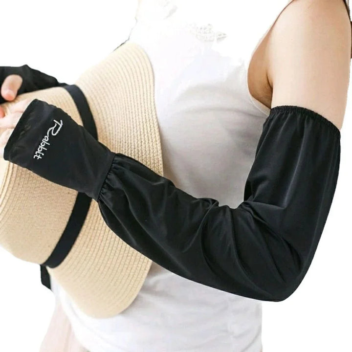 Person wearing white sleeveless top and black sun protection arm sleeves holding a beige straw hat