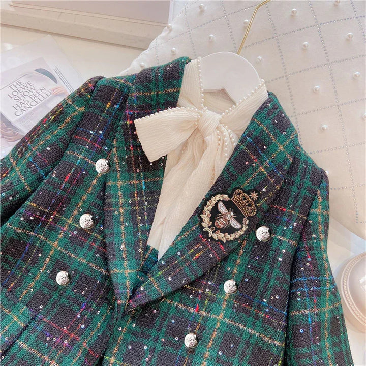Green and black plaid tweed blazer with silver buttons, bee and crown brooch, and ivory bow blouse