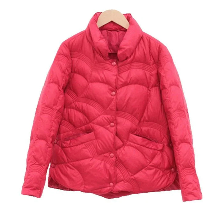 Red quilted puffer jacket with button closure and pockets on wooden hanger