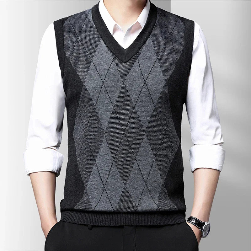 Man wearing black and gray argyle V-neck sweater vest over white shirt with rolled sleeves