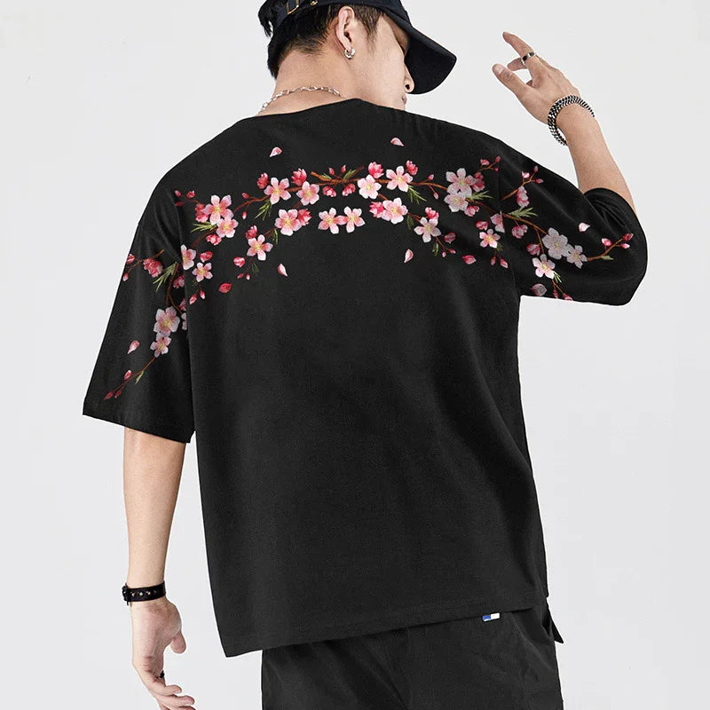 Man wearing black oversized t-shirt with pink cherry blossom floral print on back and sleeves
