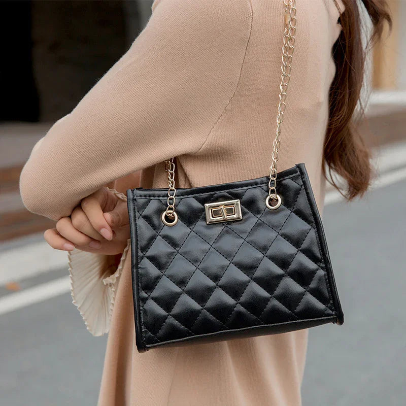 Woman wearing beige coat carrying stylish black quilted handbag with gold chain strap outdoors