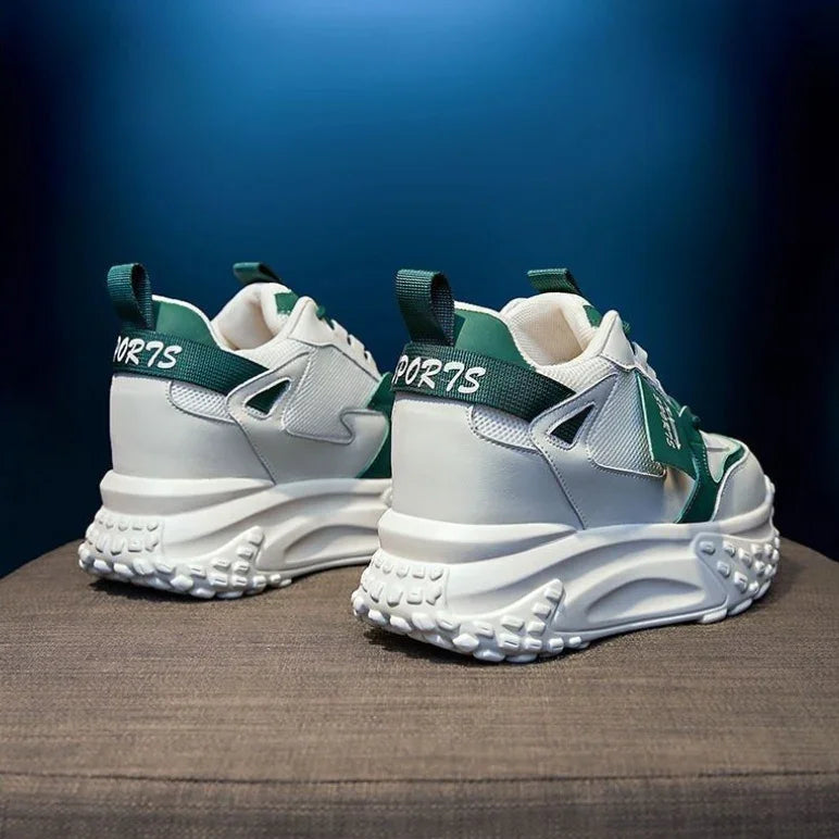 Pair of white and green chunky sports sneakers with textured soles on brown surface