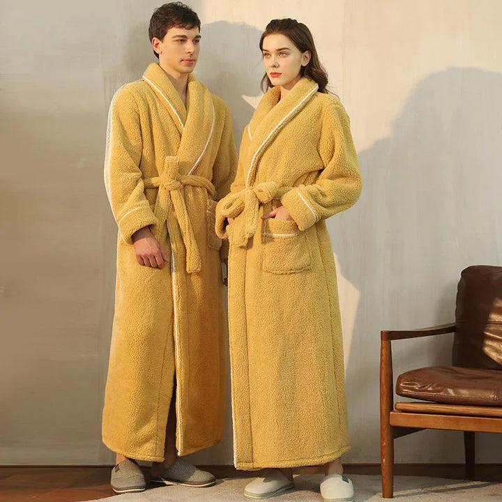 Man and woman wearing matching yellow fleece bathrobes with white trim indoors next to wooden chair