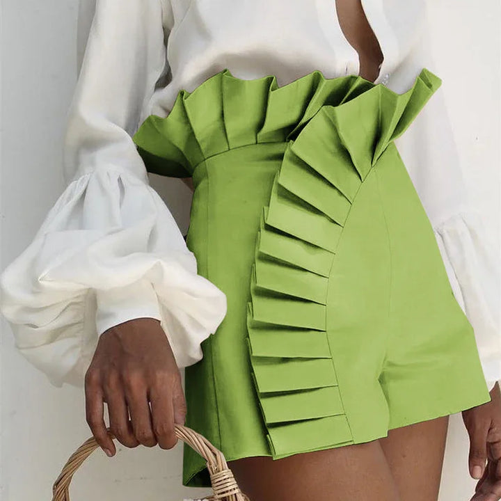 Woman wearing high-waisted lime green shorts with ruffle detailing and a white blouse with puffed sleeves