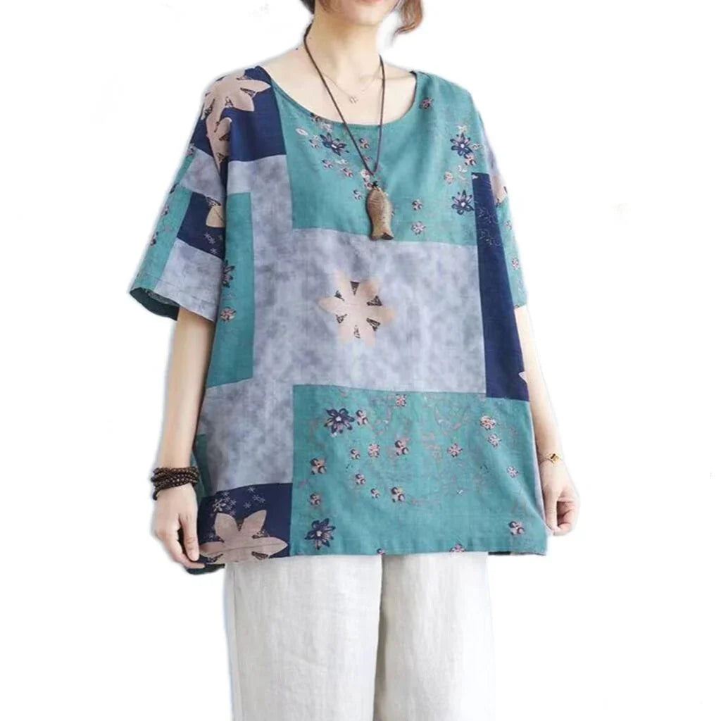 Woman wearing loose patchwork floral print blouse with blue, teal, and gray blocks and light linen pants