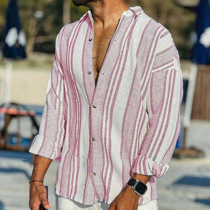 Man wearing casual white and red striped button-up shirt with rolled sleeves outdoors