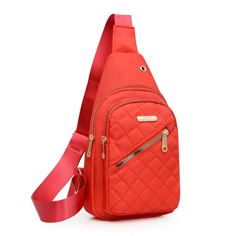 Red quilted crossbody sling bag with gold zippers and adjustable strap on white background