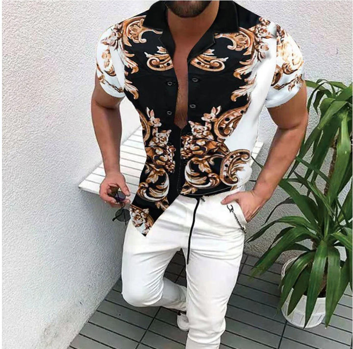Man wearing black and white short-sleeve floral patterned shirt paired with white pants indoors