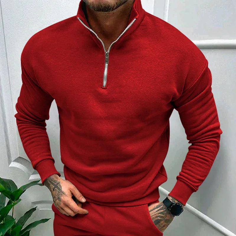 Man wearing a red quarter-zip sweatshirt and matching red pants with tattooed hands and a black watch