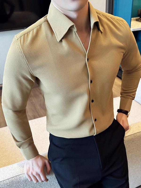 man wearing beige textured long-sleeve shirt with black buttons and black pants in indoor setting