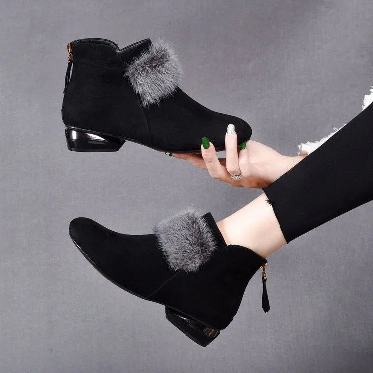 Black suede ankle boots with gray fur trim and low metallic heels worn by model in black leggings
