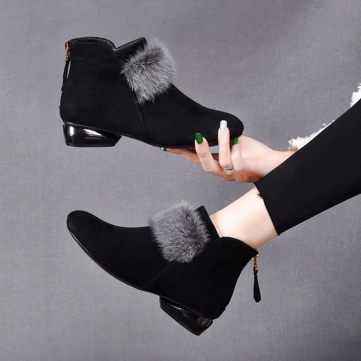 Black suede ankle boots with gray fur trim and low metallic heels worn by model in black leggings