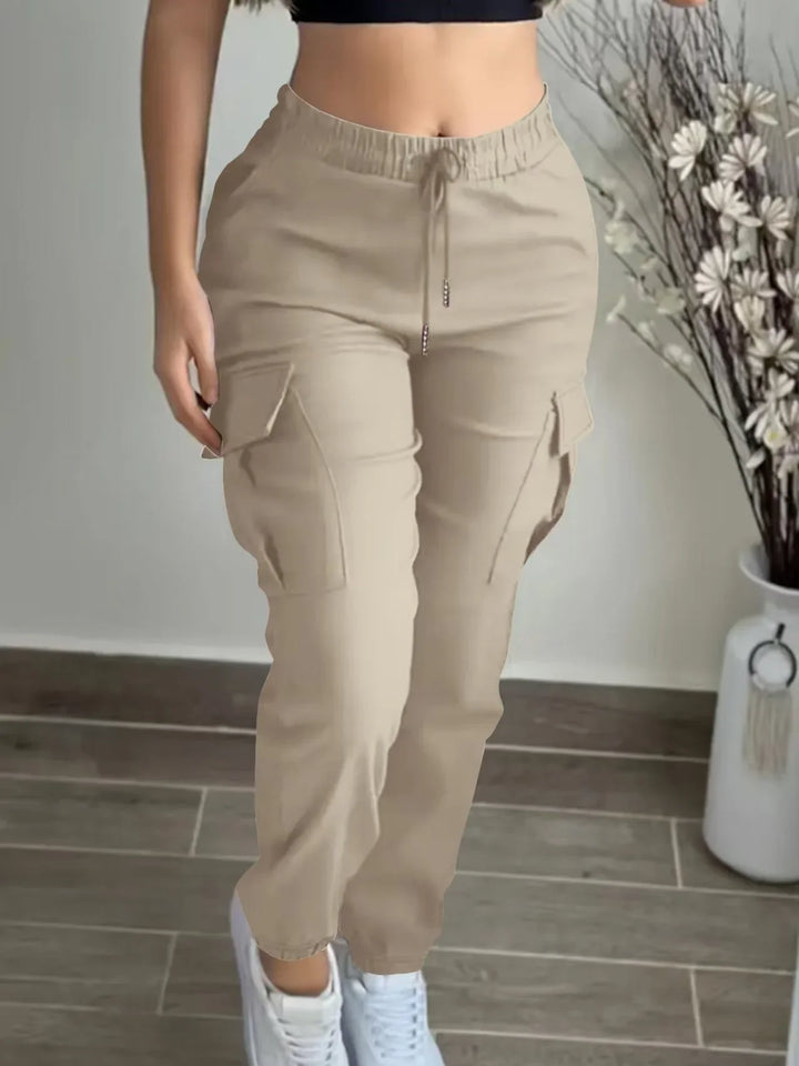 Woman wearing beige cargo pants and white sneakers standing indoors on wooden floor