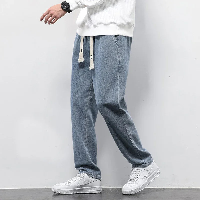 Casual loose-fit light blue denim jeans with white drawstring paired with white sneakers and white sweater