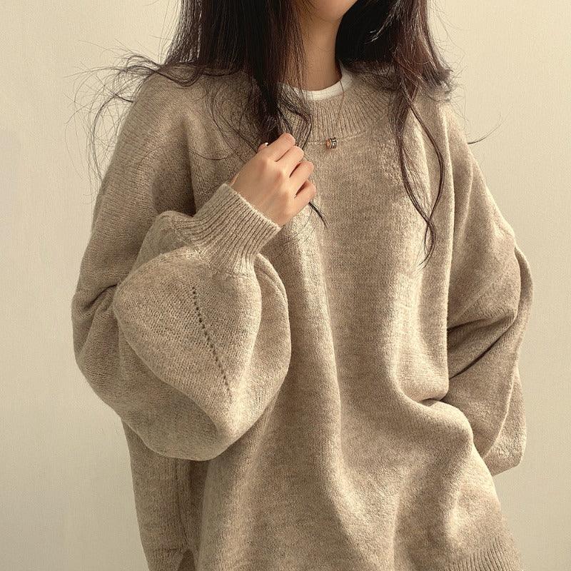 Woman wearing oversized beige knit sweater with balloon sleeves and delicate necklace