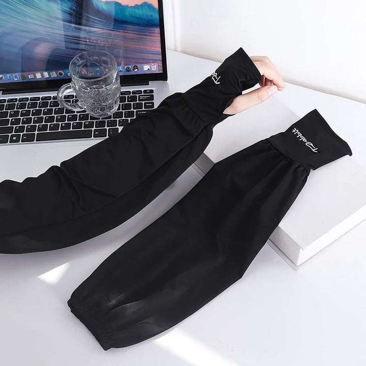 Black waterproof arm sleeve covers on a white table next to a laptop and glass cup