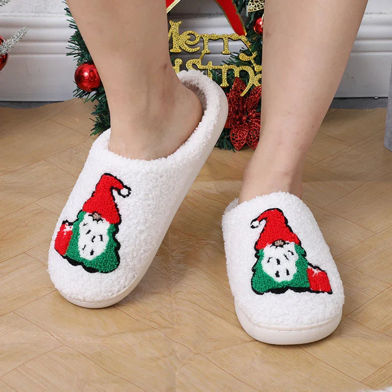 Person wearing white fuzzy Christmas slippers with Santa Claus embroidery on wooden floor