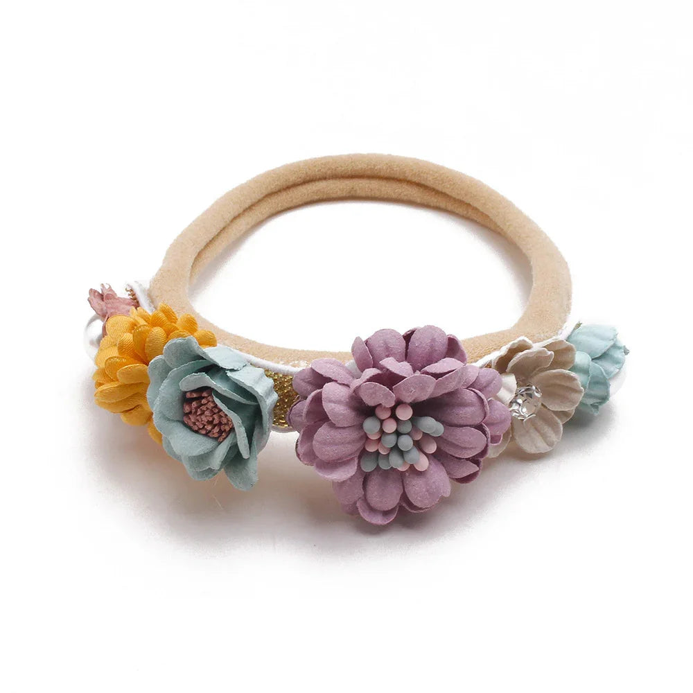 Beige elastic hairband decorated with pastel fabric flowers in yellow, light blue, purple, and beige