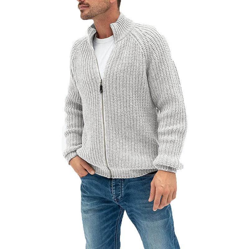 Man wearing light gray chunky knit zip-up sweater and blue jeans with hands in pockets