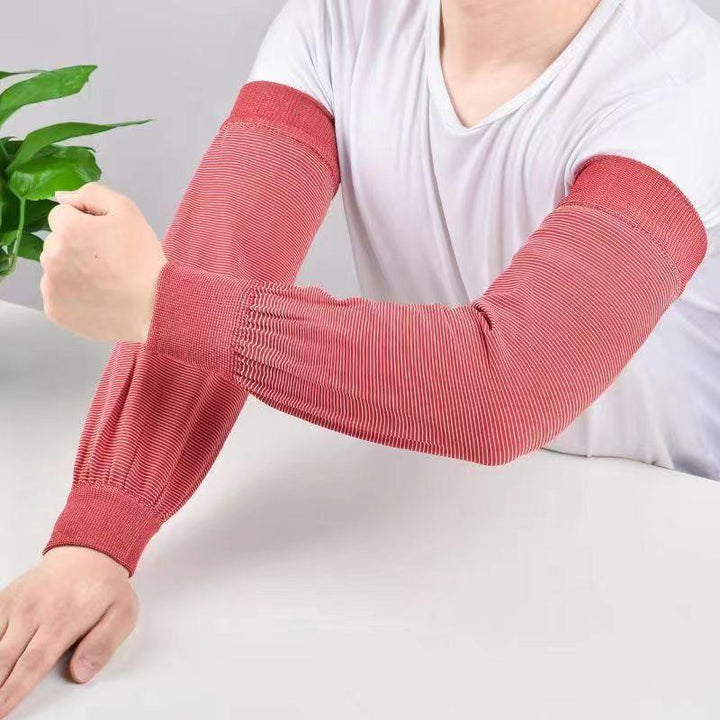 Person wearing red striped arm sleeves and white shirt, resting arms on white table with green plant background
