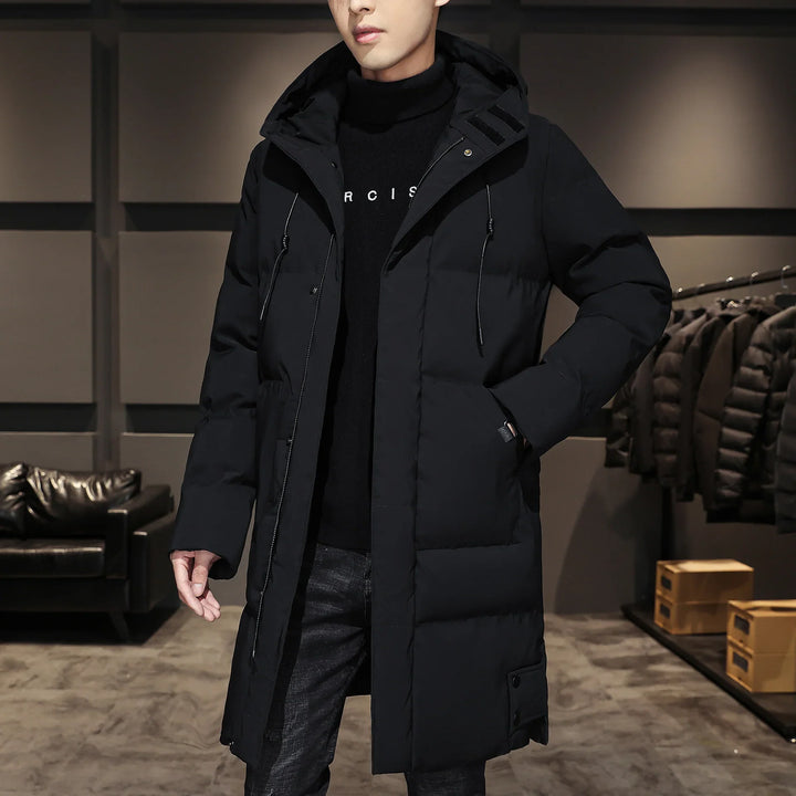 Man wearing long black puffer coat with hood in modern clothing store showroom