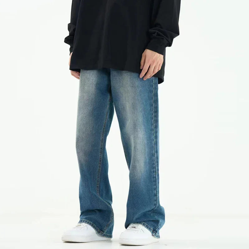 Person wearing loose fit faded blue jeans, black oversized top, and white sneakers