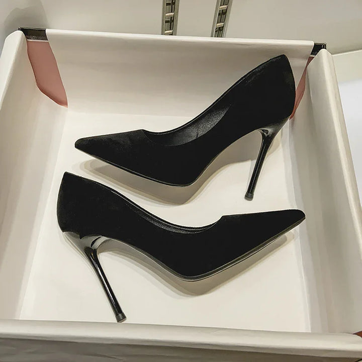 Pair of elegant black velvet stiletto heels with pointed toes in a white box