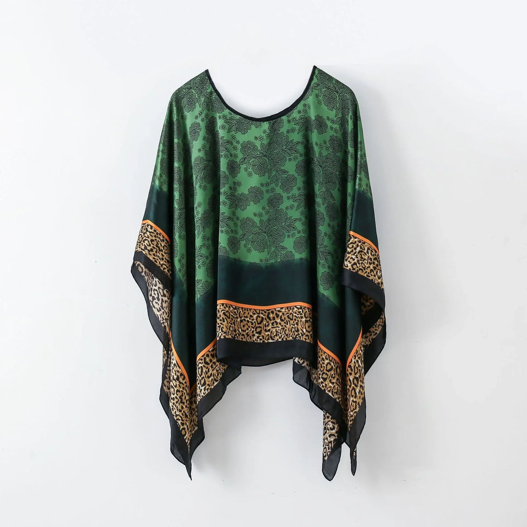 Green floral and leopard print poncho with black and orange borders hanging on white background