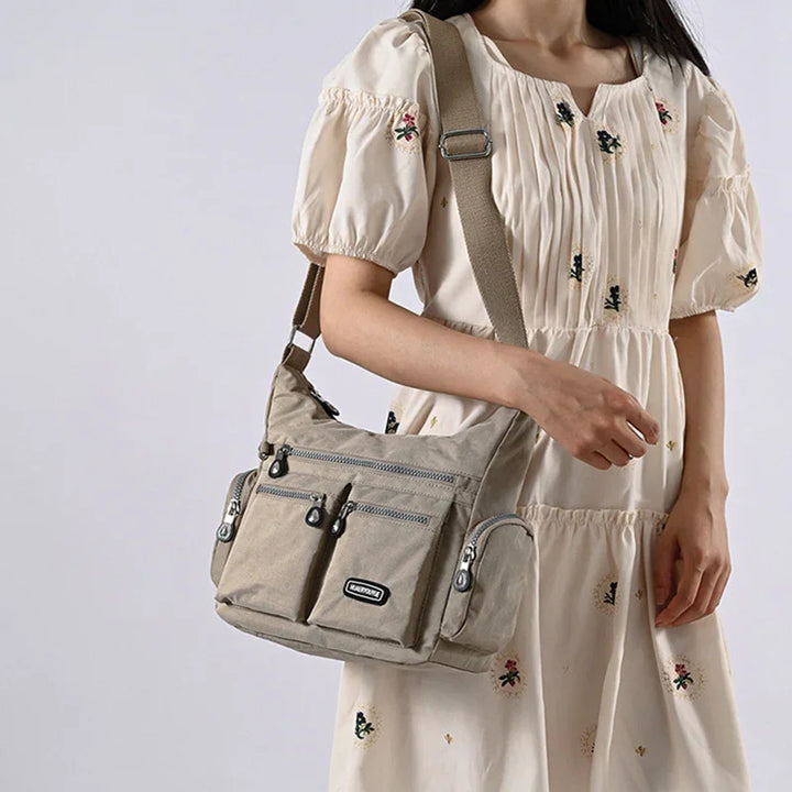 Woman wearing cream floral dress carrying beige multi-pocket casual shoulder bag
