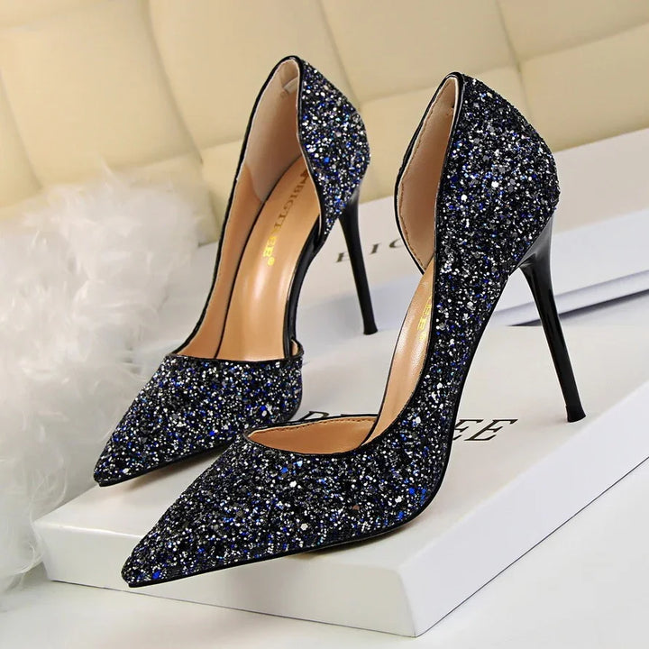 Elegant black glitter high heel shoes with pointed toes on white box with soft background