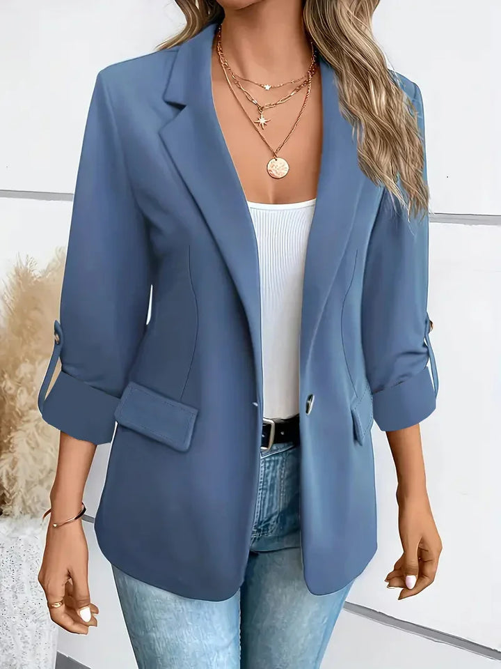 Woman wearing blue 3/4 sleeve blazer with white tank top and layered gold necklaces